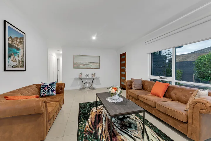 The living room at 3 Phelan Drive looking toward the front door, with seating for several people and a large front window.